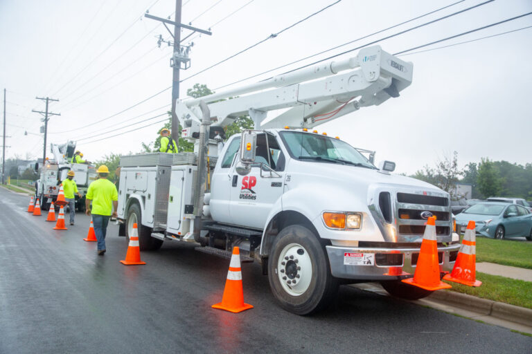 Sun Prairie Utilities lineworkers setting up orange safety cones around two bucket trucks, taken in 2021 or 2022.